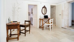 Ein Zimmer mit einem Holztisch, einem Stuhl, einem Laptop und einem Spiegel an der Wand.