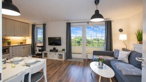 Un soggiorno moderno con un divano, un tavolo da pranzo, una TV e un balcone con vista.