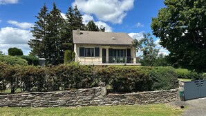 A two-story house with a tiled roof, a balcony with a railing, and a stone wall in the foreground. - Holiday Home "La Maison De Campagne" with Mountain View, Private Terrace and Garden (Salles-Curan)