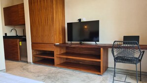 Ett litet rum med ett skrivbord i trä, en tv, en stol och ett litet pentry.