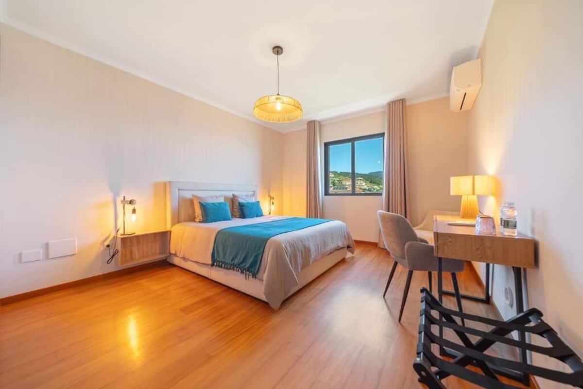 Habitación de hotel con cama, escritorio, silla y vistas al paisaje.