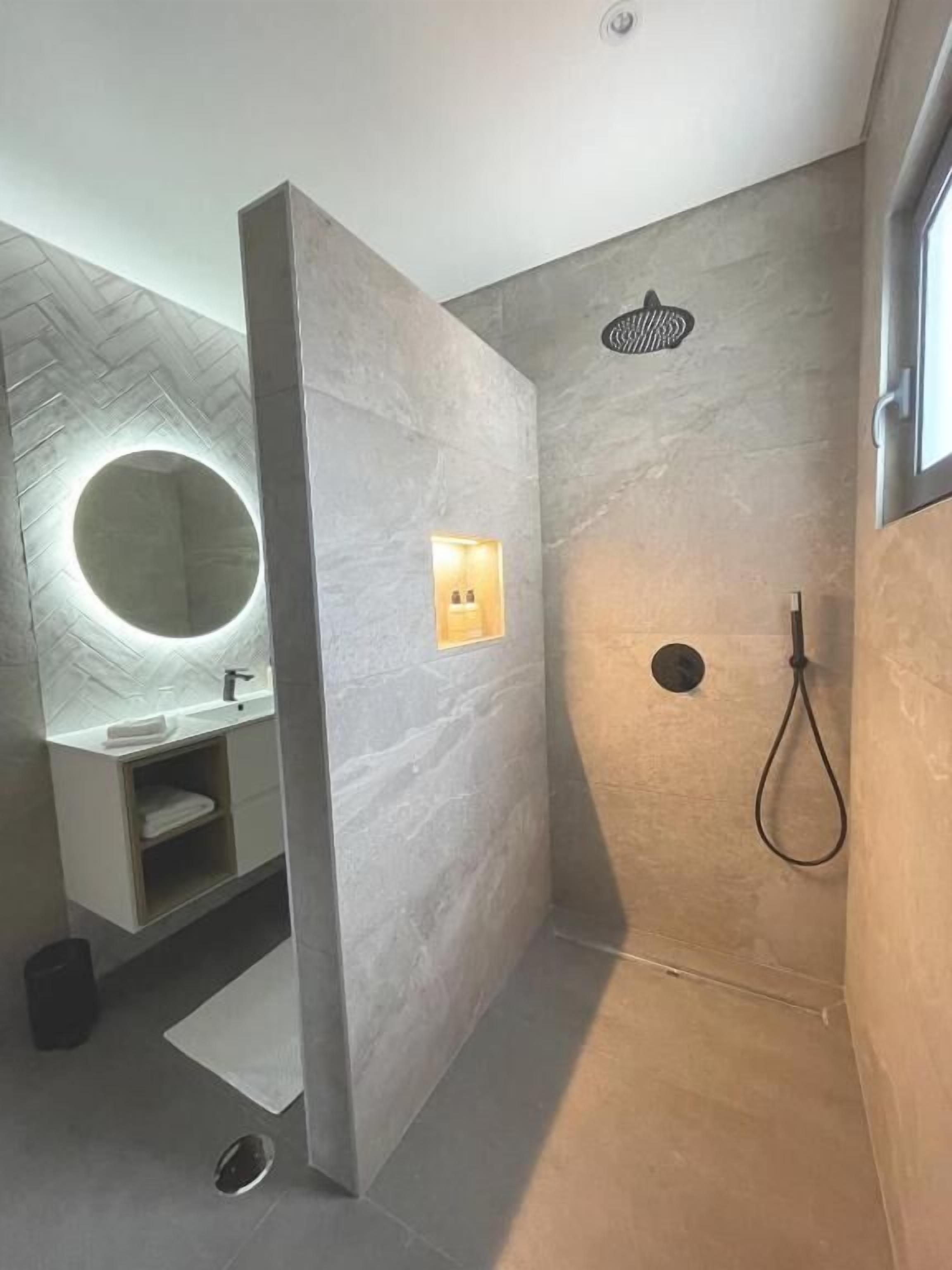 Un baño moderno con ducha, lavabo con espejo y un perchero para toallas.
