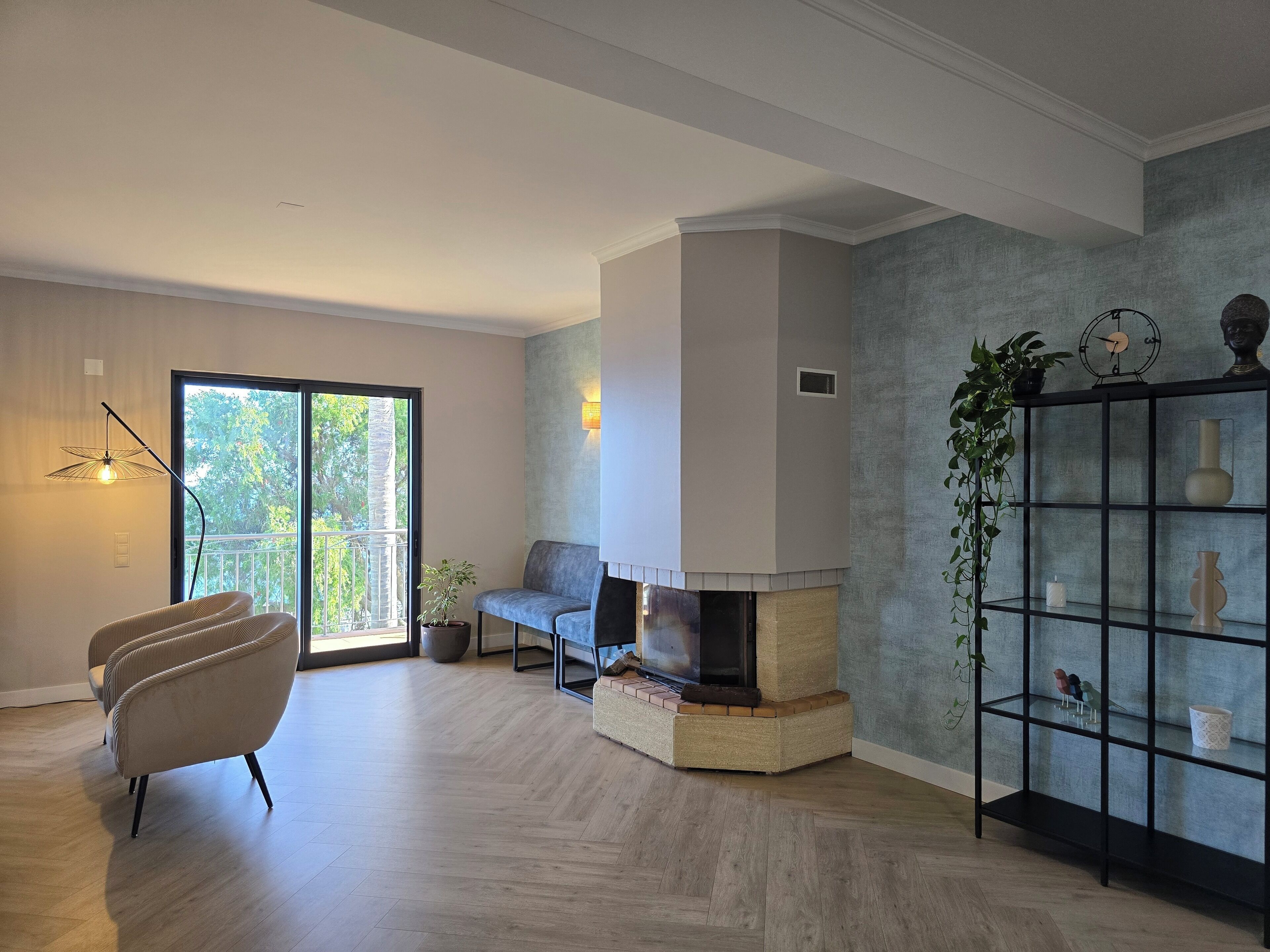 A modern living room with a fireplace, a sofa, a chair, and a bookshelf.