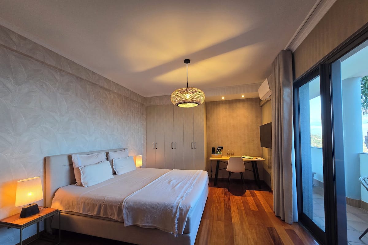 Un dormitorio moderno con una cama grande, un escritorio y vistas a través de una puerta corredera.