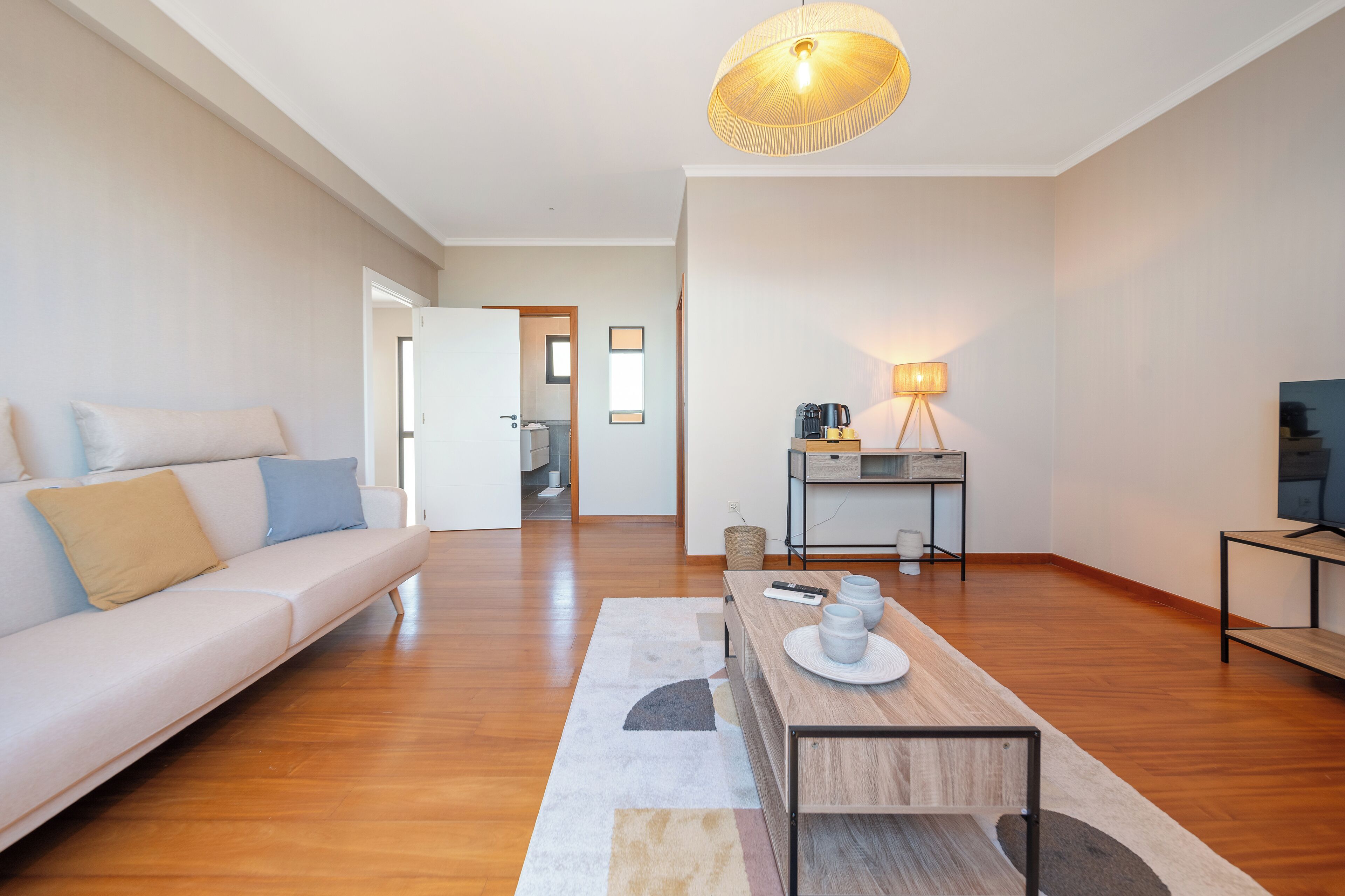 A modern living room with a sofa, a coffee table, and a lamp.
