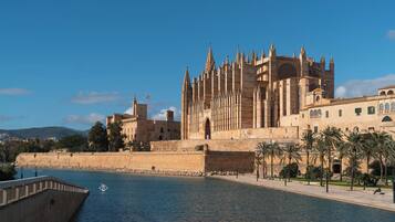 Una catedral histórica con una alta torre central, una muralla fortificada y un río al frente.