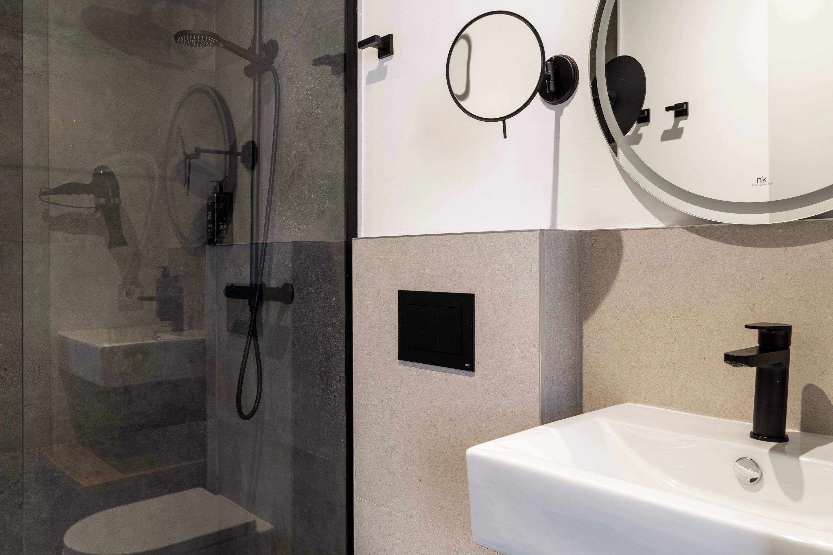 A modern bathroom with a glass-enclosed shower, a white sink, and a wall-mounted mirror.