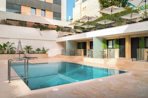 Una piscina con una barandilla de seguridad metálica, rodeada de un solado de baldosas.