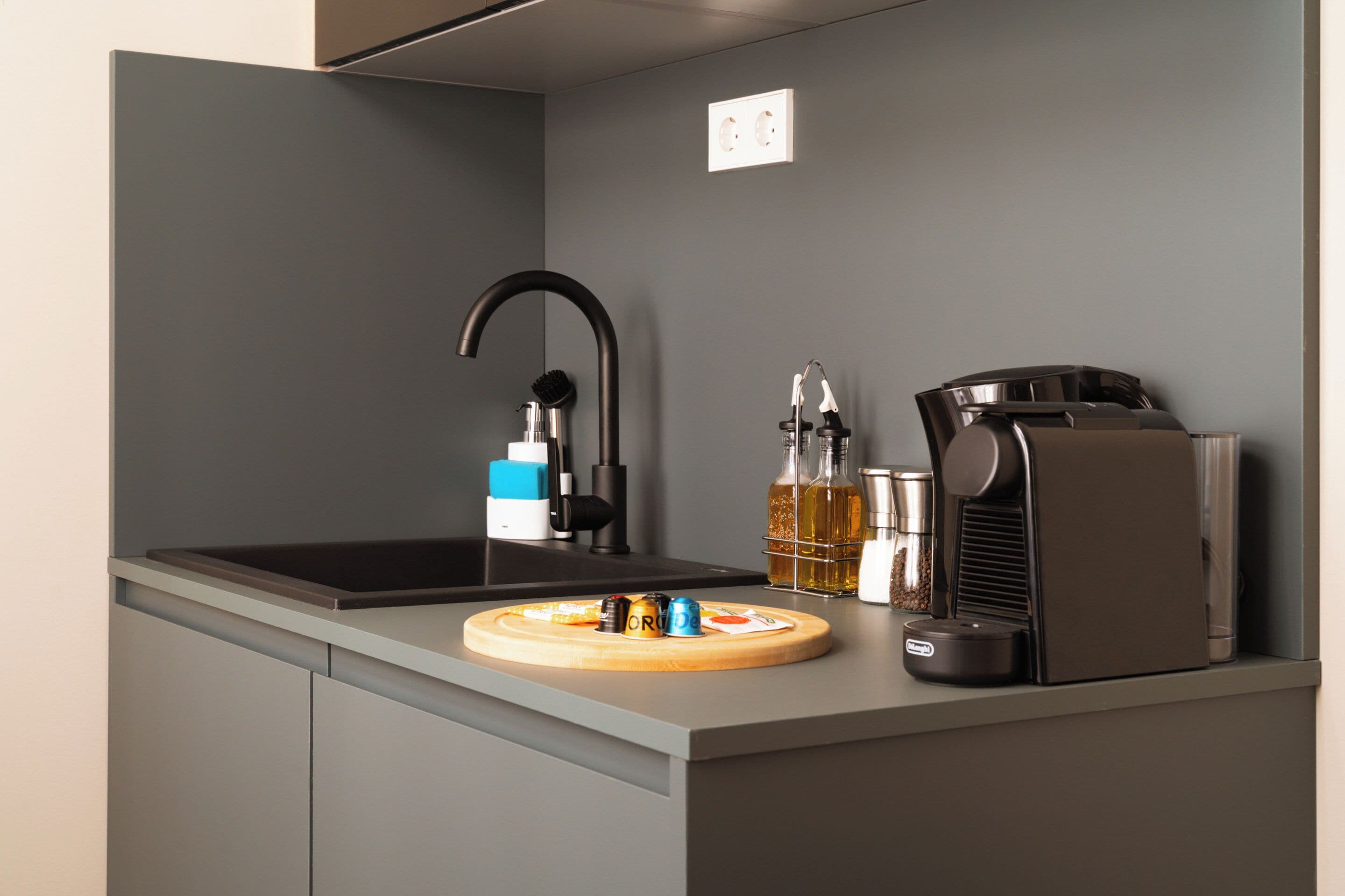 A modern kitchen with a built-in sink, a coffee machine, and a bottle of olive oil.