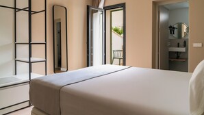 Un dormitorio con cama, espejo, armario y puerta que da a un balcón.