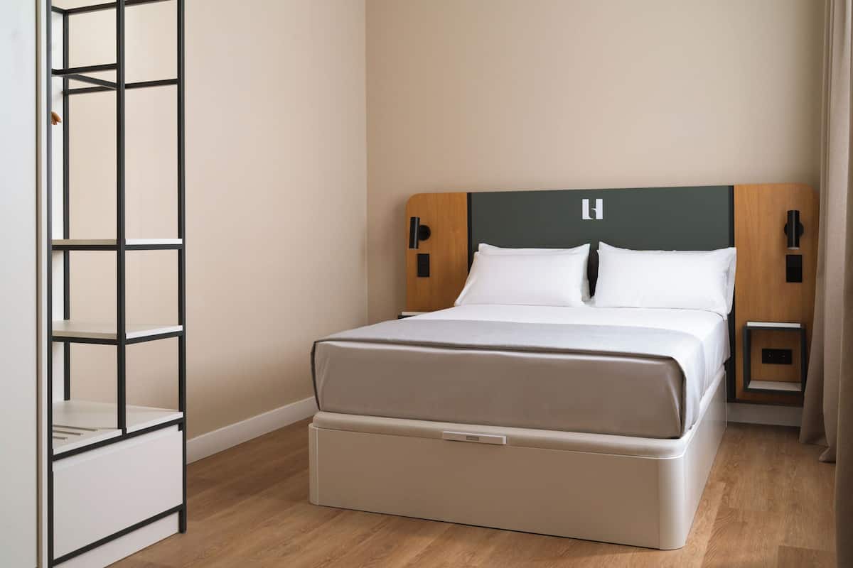 A modern bedroom with a bed, bedside tables, and a built-in wardrobe.