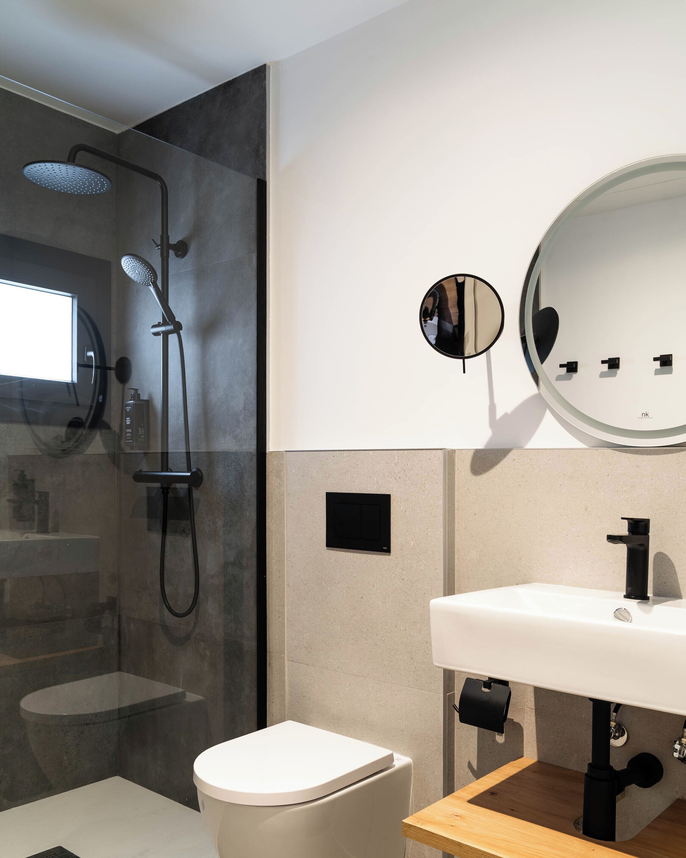A modern bathroom with a glass-enclosed shower, a white sink, and a toilet.
