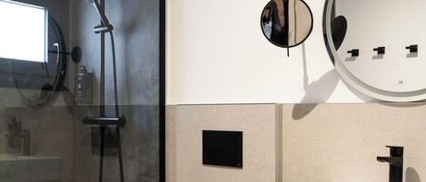 A modern bathroom with a glass-enclosed shower, a white sink, and a toilet.