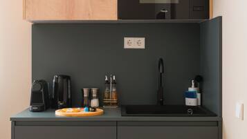 Ett kompakt kök med mikrovågsugn, kaffebryggare och ett litet handfat.