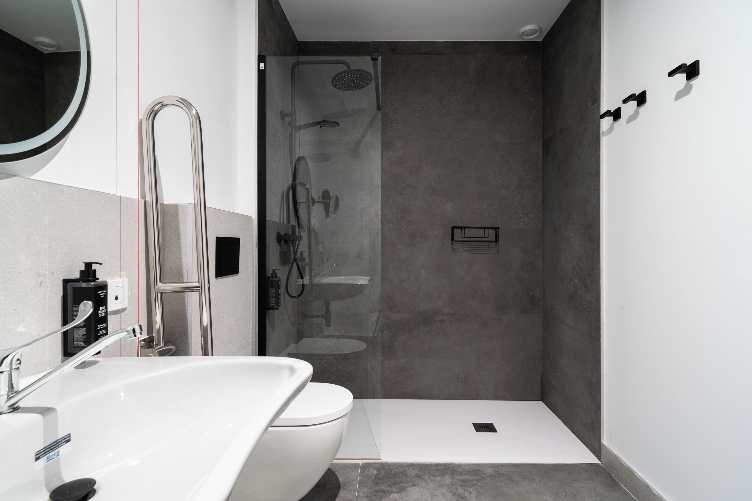 Une salle de bain moderne avec un lavabo, des toilettes et une zone de douche, le tout de couleur blanche.