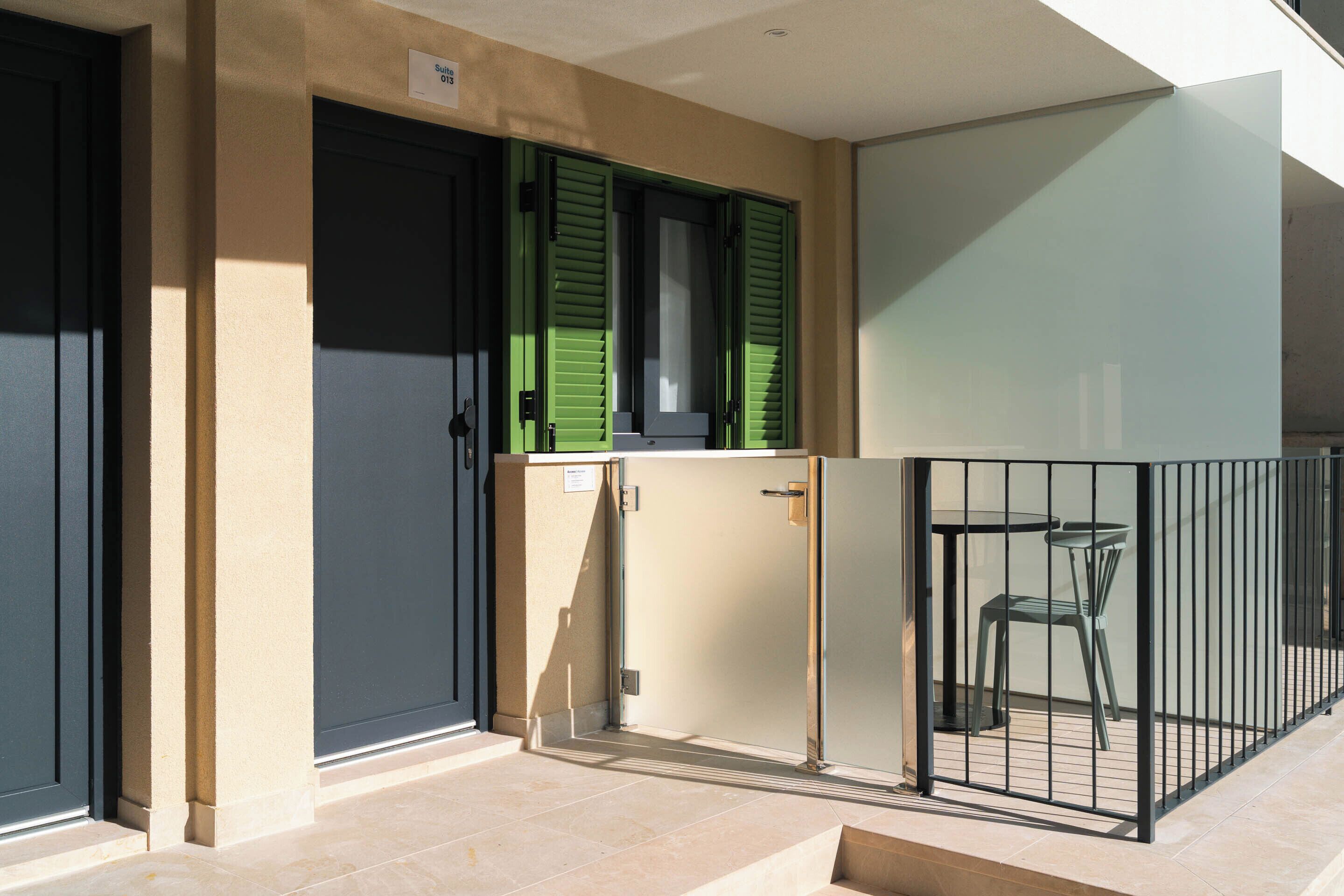 Un apartamento pequeño con balcón, una kitchenette y una zona de comedor con dos sillas.