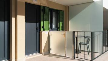 Un apartamento pequeño con balcón, una kitchenette y una zona de comedor con dos sillas.