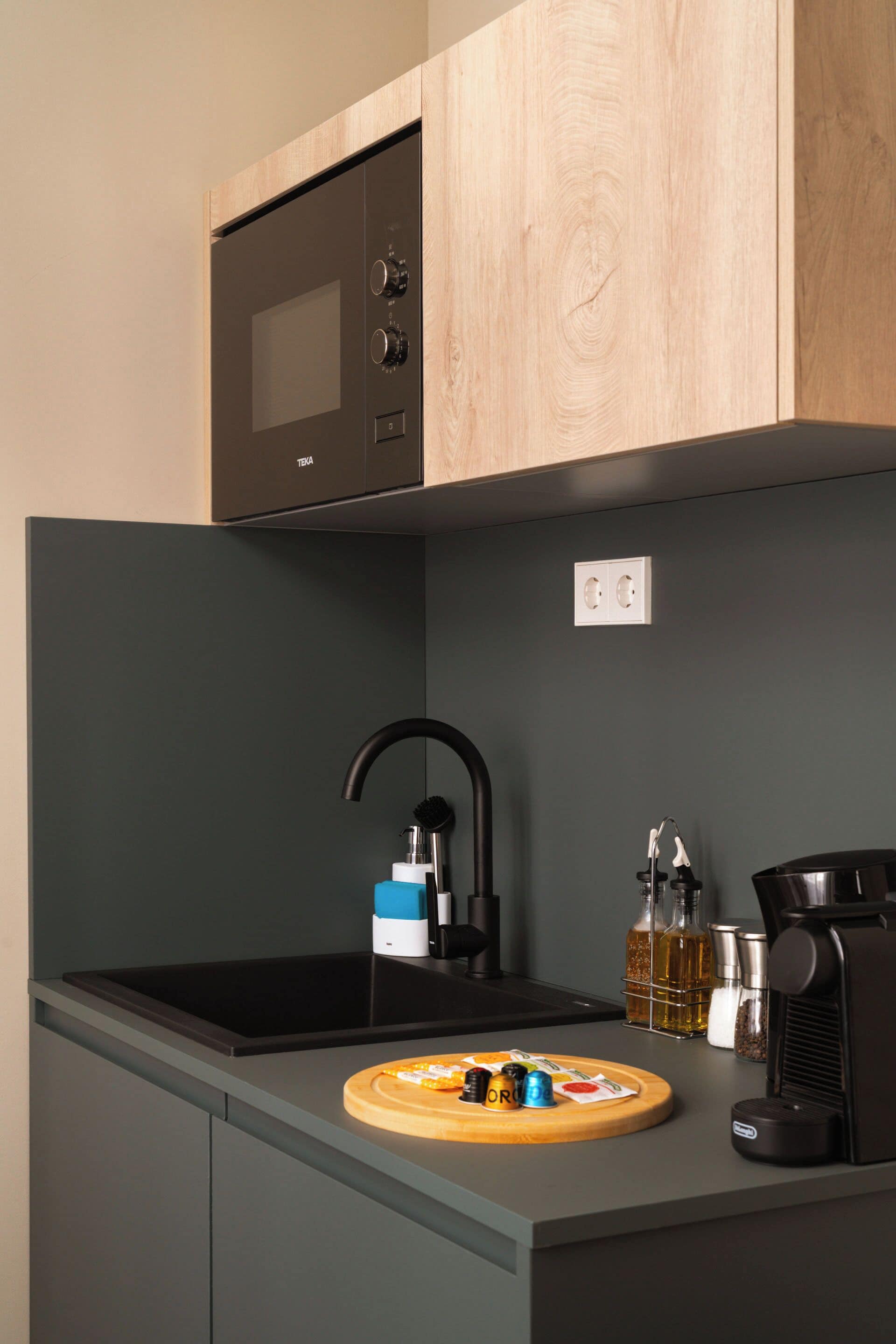 A modern kitchen with a black stove, a sink, and a wooden cutting board with food items.