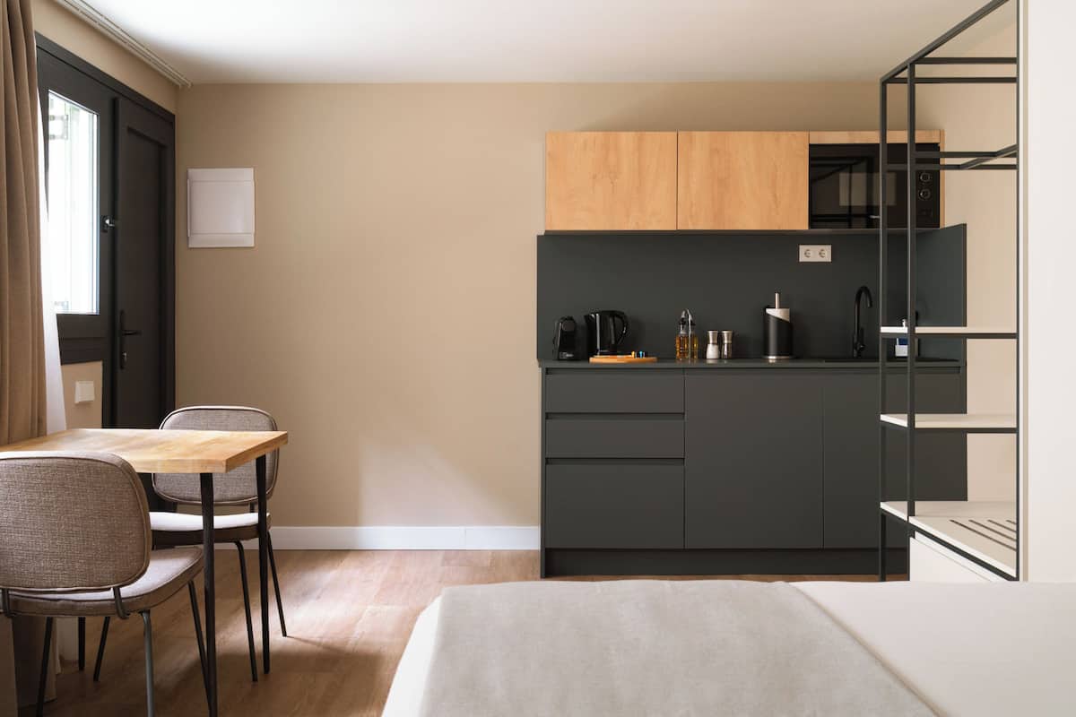 A compact kitchen with a dining area, a bed, and a window with curtains.