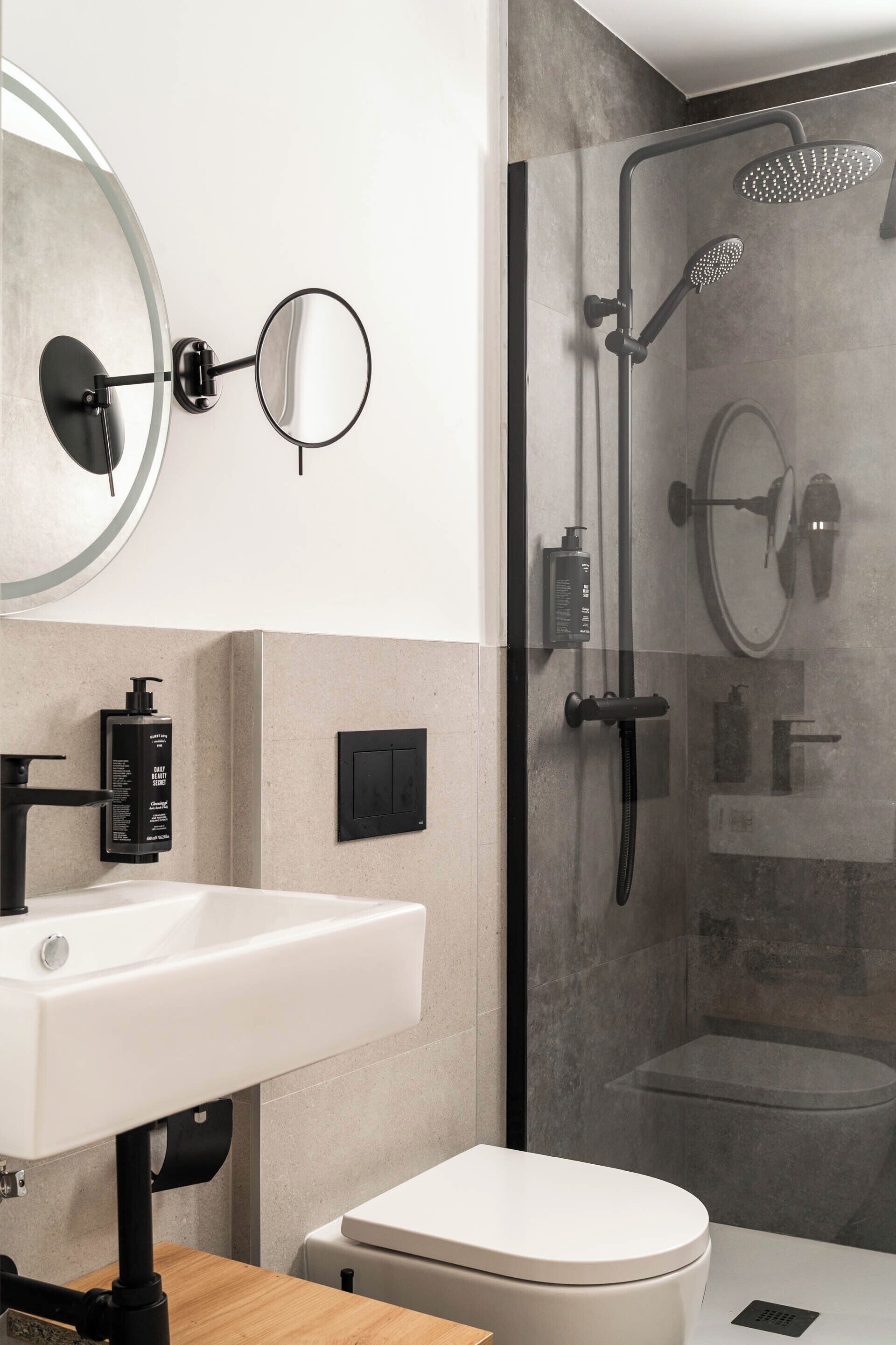 A modern bathroom with a glass-enclosed shower, a white sink, and a toilet.