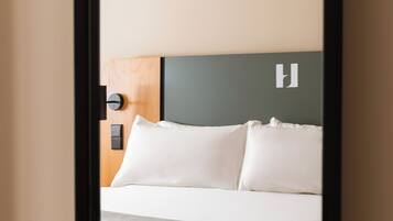 A hotel room with a bed, a headboard, and a nightstand.