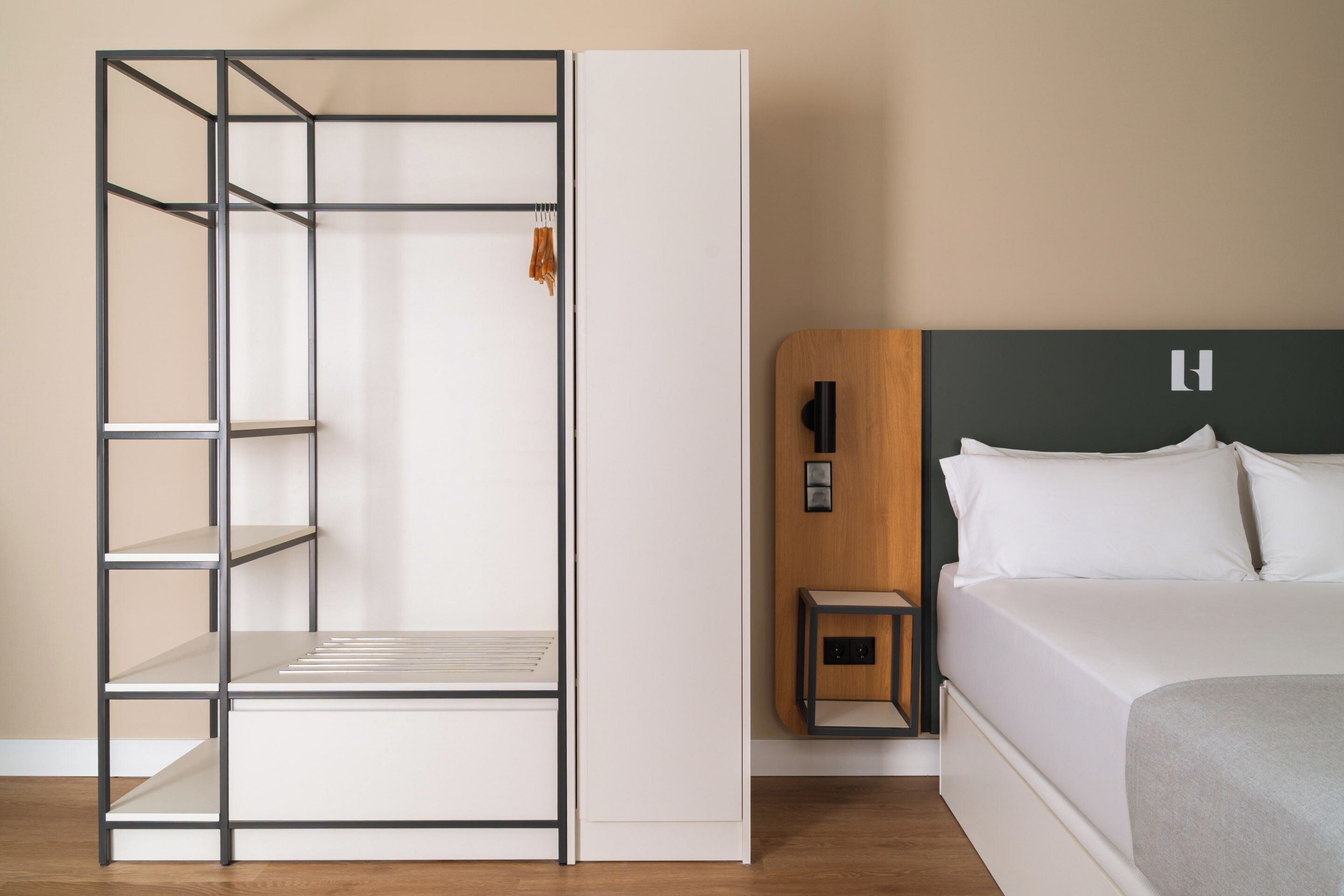A modern bedroom with a bed, a wardrobe with shelves, a nightstand, and a wooden headboard.