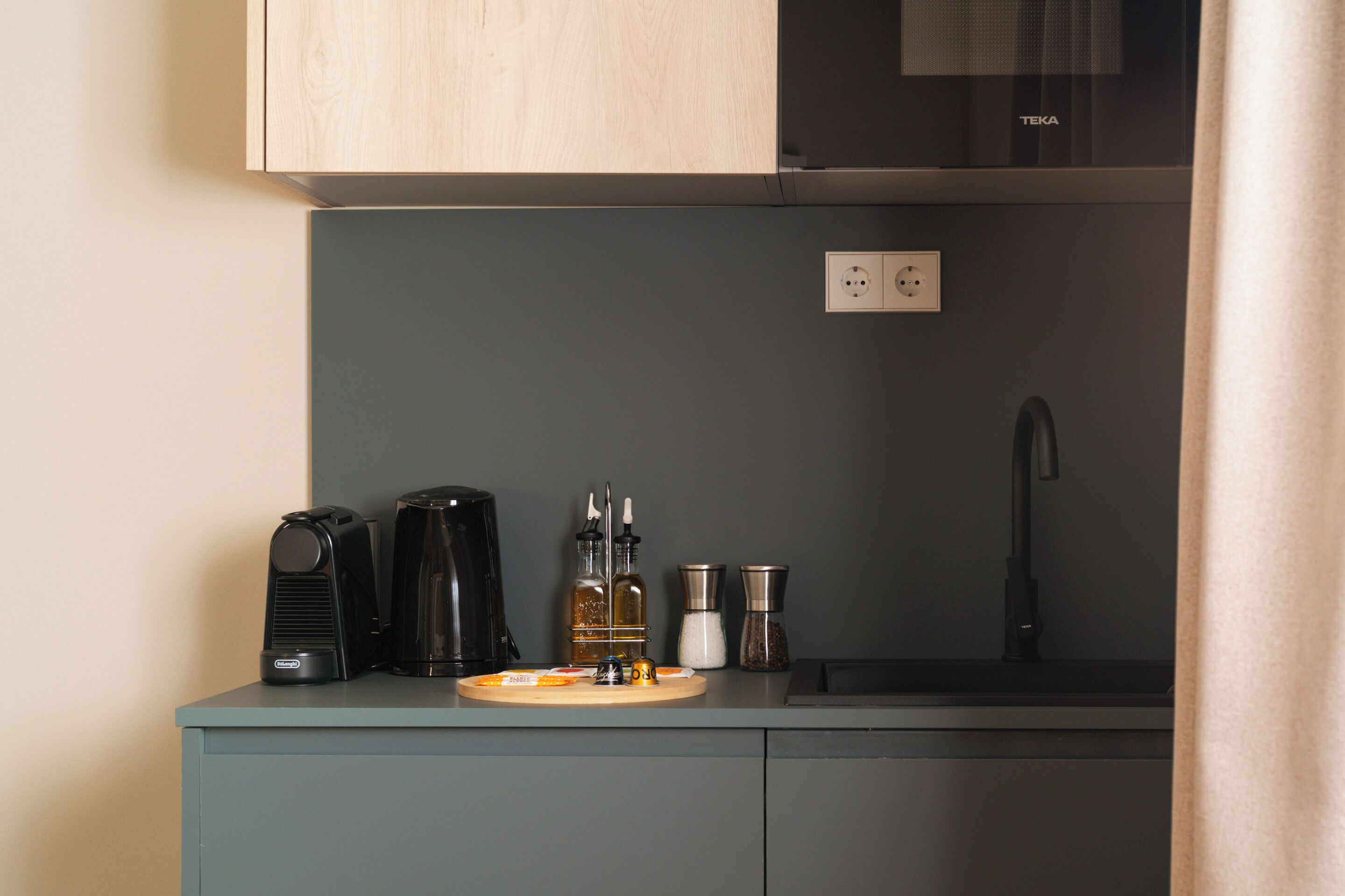A kitchenette with a coffee maker, a kettle, a tea pot, and a salt and pepper set.