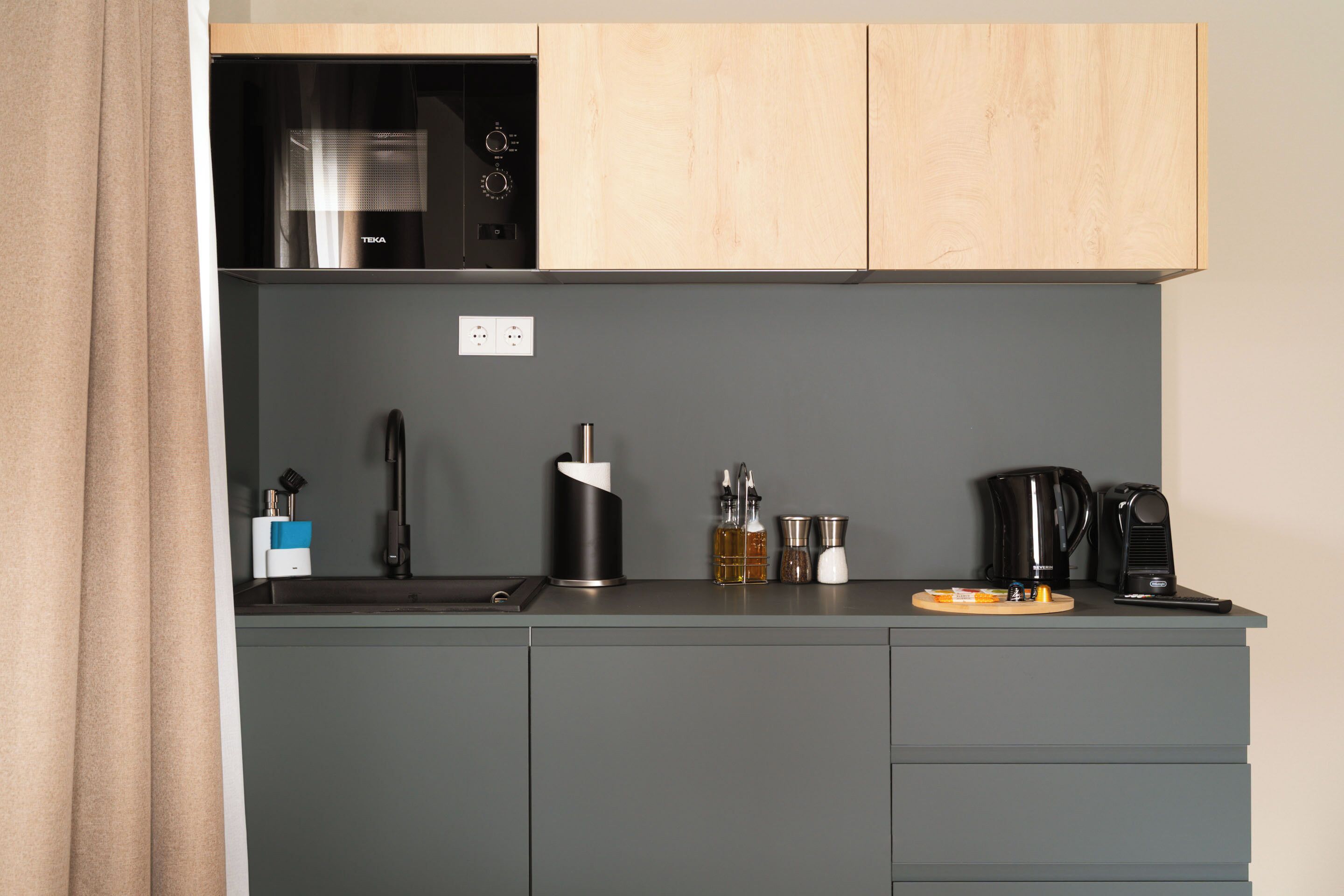 A modern kitchen with a built-in microwave, a coffee maker, and a kettle on the counter.