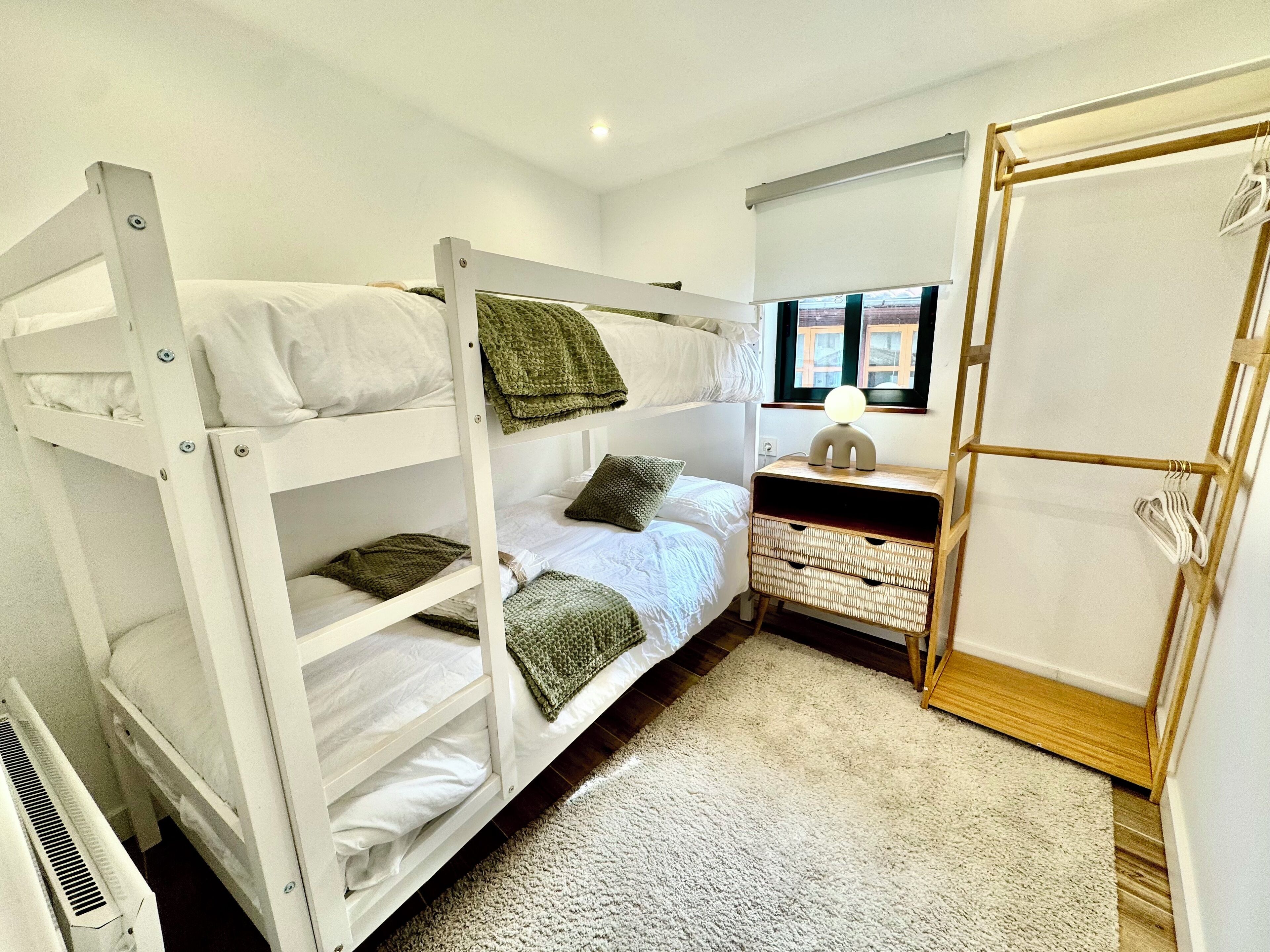 Dormitorio con literas, una mesita de noche, una lámpara y ventana con vistas.
