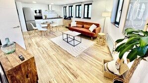 A modern living room with a sofa, coffee table, and dining area. - Gestviva Casa Urbanin III (Cudillero)