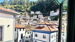 A view of a hillside town with terracotta-tiled buildings, a prominent blue and white building with a sign reading "LA CASA DE JULIA," and a cobblestone street. - Gestviva Casa Urbanin III (Cudillero)