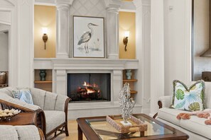 A living room with a fireplace, two sofas, a coffee table, and wall-mounted lamps.