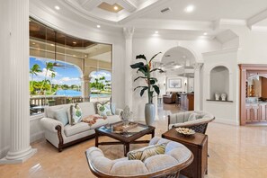 A spacious living area with a large window, a sofa, a coffee table, and a dining area in the background.
