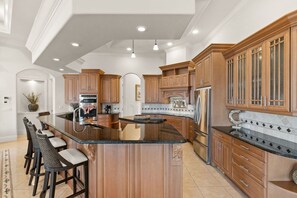 A spacious kitchen with a large island, wooden cabinets, and modern appliances.