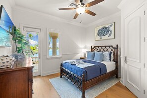 Un dormitorio con cama de madera, ventilador de techo, una ventana grande y una puerta que da a un balcón.