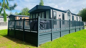 A mobile home with a fenced outdoor area, a covered porch, and a car parked inside. - Host Stay Coopers Corner (York)