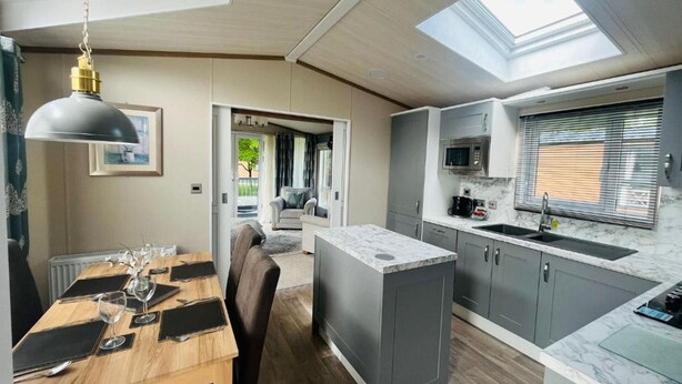 A compact kitchen with a microwave, sink, and a dining area with a table set for two. - Host Stay Coopers Corner (York)