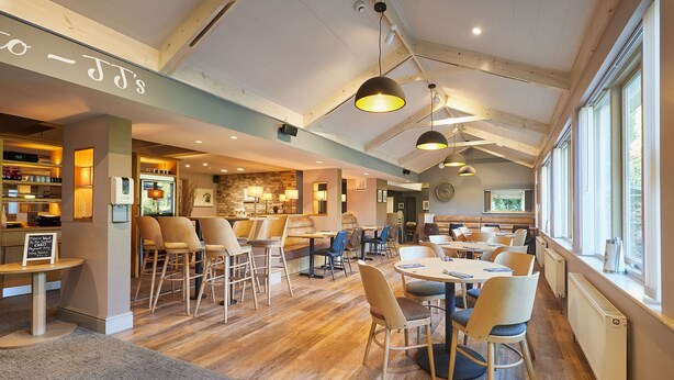 A spacious restaurant with wooden floors, multiple seating areas, and large windows providing natural light. - Host Stay The Braunston Lodge (York)