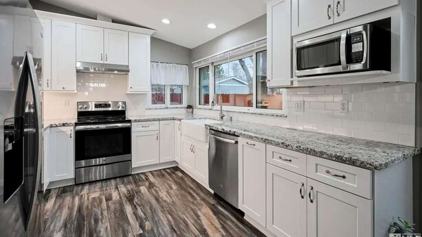 A modern kitchen with white cabinets, stainless steel appliances, and a granite countertop. - Family 4BR Home With Patio by Willowcreek Park (Sparks)