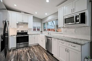 Una cocina moderna con armarios blancos, electrodomésticos de acero inoxidable y encimera de granito.
