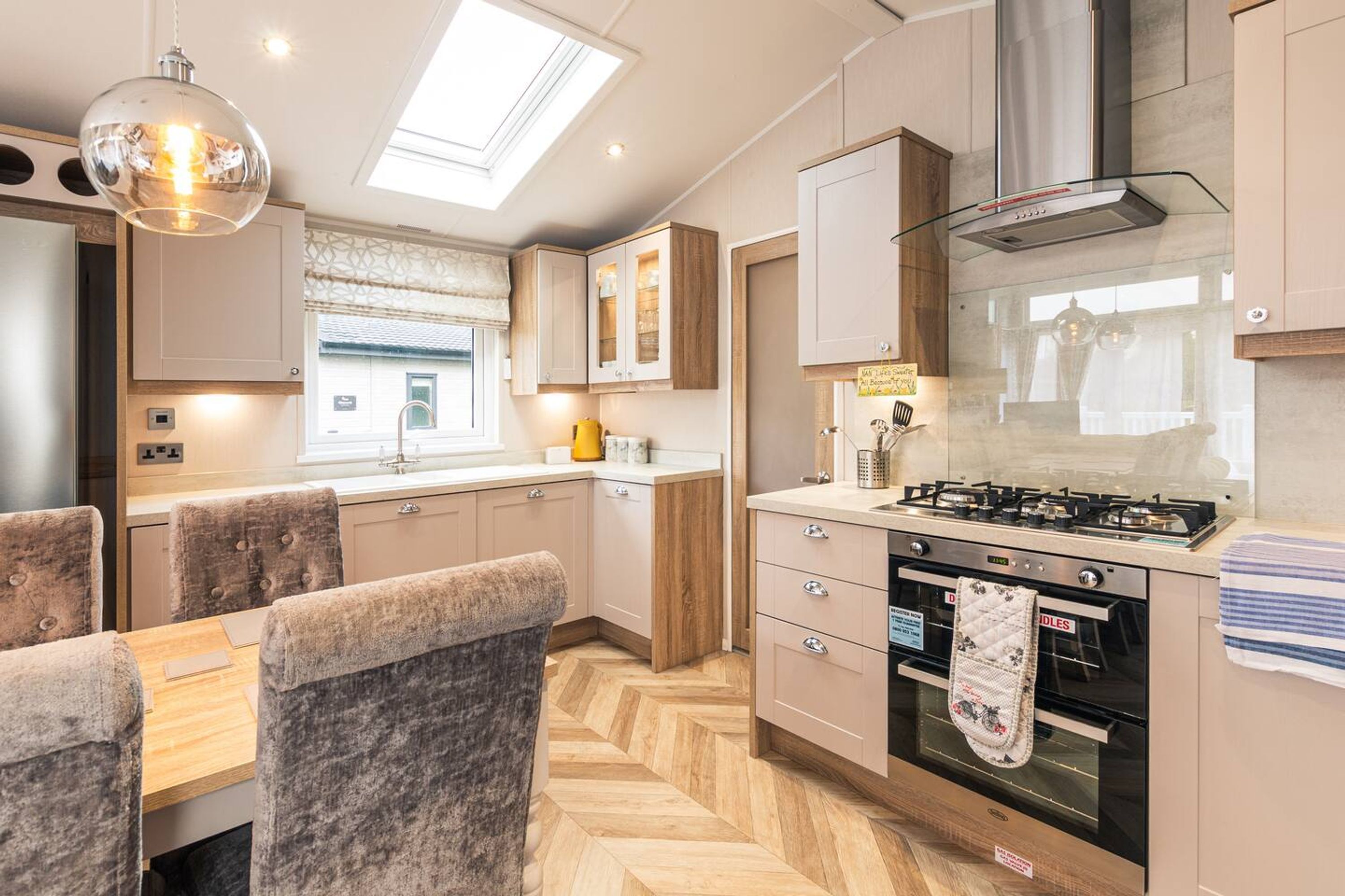 A modern kitchen with a gas stove, oven, and a skylight above the dining area.