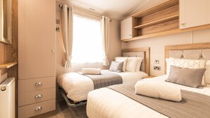 A bedroom with two beds, a wardrobe, and a window with curtains. - Host Stay Lakeside Retreat (York)
