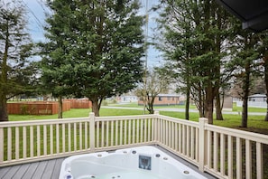 A hot tub on a wooden deck with a white railing, surrounded by trees and a grassy yard. - Host Stay Lotus Lodge (York)