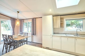 A modern kitchen with white cabinets, a built-in sink, and a window overlooking a residential area. - Host Stay Lotus Lodge (York)
