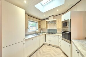 A modern kitchen with a skylight, stainless steel appliances, and light wood cabinetry. - Host Stay Lotus Lodge (York)