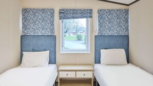 A twin room with two beds, a window, and a small wooden nightstand with drawers. - Host Stay Lotus Lodge (York)