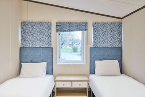 A twin room with two beds, a window, and a small wooden nightstand with drawers. - Host Stay Lotus Lodge (York)