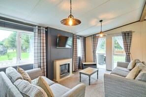 A living room with a fireplace, sofa, and television. - Host Stay Lotus Lodge (York)