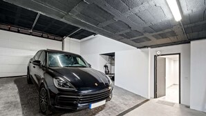 A black car parked in a garage with a concrete floor and a garage door in the background. - Villa Pinares de San Antón Sea, City & Mountain Views (Málaga)