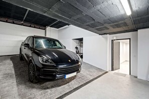 Ein schwarzes Auto steht in einer Garage mit Betonboden und einer Garagentür im Hintergrund.